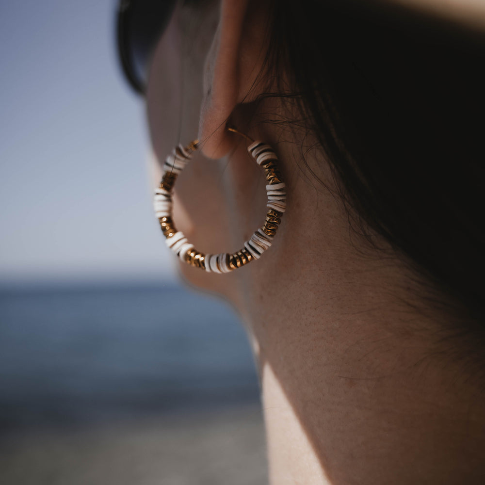 
                      
                        Tossa de Mar | Boucles d'oreilles / créoles en acier inoxydable et pierres naturelles | Coquillage et hématite | Doré
                      
                    